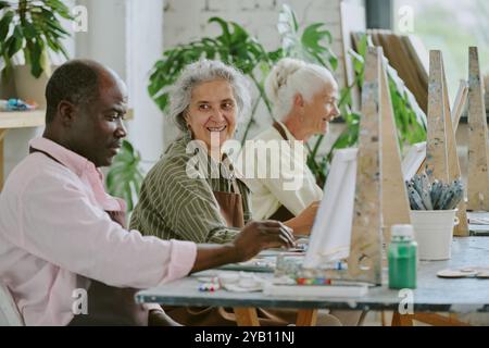 Personnes biraciales retraitées s'amusant ensemble tout en peignant sur toile ensemble dans le studio de dessin Banque D'Images