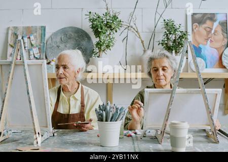 Deux meilleurs amis seniors peignant sur toile ensemble pendant l'art thérapie Banque D'Images