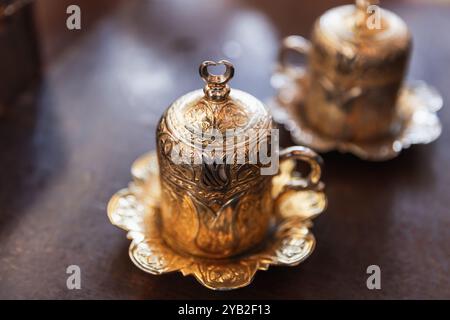 Le café turc est servi dans des tasses fermées vintage de luxe avec une décoration arabesque dorée. Gros plan avec flou sélectif Banque D'Images