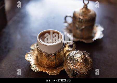 Le café turc est servi dans de petites tasses vintage de luxe avec une décoration arabesque dorée. Gros plan avec flou sélectif Banque D'Images