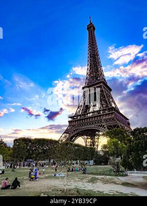 Tour Eiffel avec des nuages de coucher de soleil et un ciel bleu avec des gens qui profitent d'un pique-nique sur la pelouse Banque D'Images