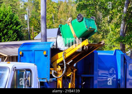 Enlèvement des ordures par les services municipaux de nettoyage en chargeant les déchets ménagers mélangés dans des camions à ordures Banque D'Images