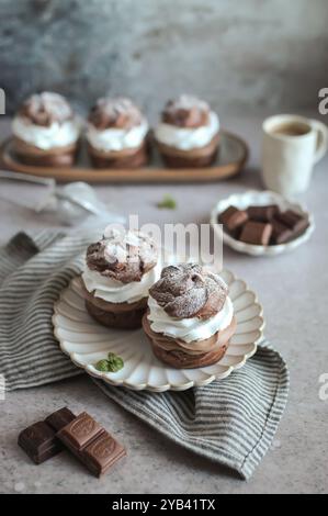 Double bouffées de crème au chocolat sur une assiette. Serviette grise dépouillée et morceaux de chocolat. Fond gris. Banque D'Images