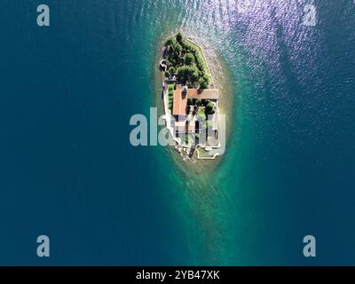 Petite île avec maison de style rétro entourée d'arbres et d'eau de lagon de mer clair Banque D'Images
