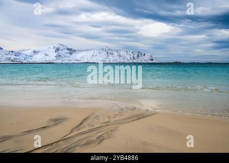 Plage de Ramberg ou Rambergstranda en hiver sur les îles Lofoten, Norvège. Paysage d'hiver avec des montagnes enneigées, plage de sable du nord et eaux claires de Banque D'Images