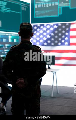 Le personnel militaire américain supervisant l'activité de guerre cybernétique dans le bureau de haute technologie, examine les renseignements top secret sur grand écran. Les experts gouvernementaux gèrent la guerre hybride, la prévention numérique des conflits. Banque D'Images