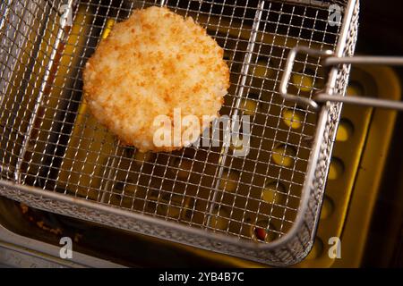 Côtelette frite dans le panier de la friteuse dans la cuisine du restaurant. Banque D'Images