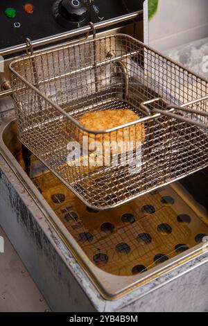 Côtelette frite dans le panier de la friteuse dans la cuisine du restaurant. Banque D'Images