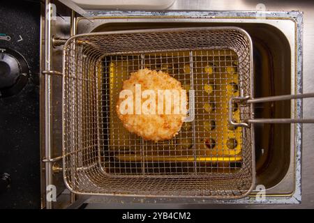 Côtelette frite dans le panier de la friteuse dans la cuisine du restaurant. Banque D'Images