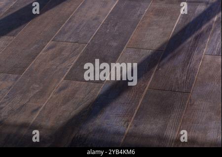 La lumière chaude du soleil se répand à l'intérieur, illuminant les tons riches d'un parquet rustique tandis que les ombres délicates dansent à travers la surface, créant un inv Banque D'Images