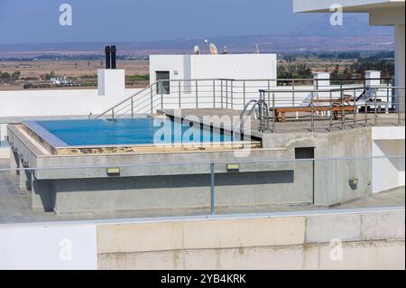 Une piscine luxueuse sur le toit invite à la détente, offrant une vue imprenable sur les montagnes lointaines et une atmosphère sereine. Des chaises longues vous attendent au bord de l'eau Banque D'Images