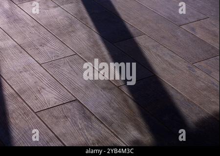 Une lumière douce pénètre dans la pièce, créant un jeu d'ombres sur la surface en bois lisse. Le grain complexe du plancher ajoute de la chaleur et du chara Banque D'Images