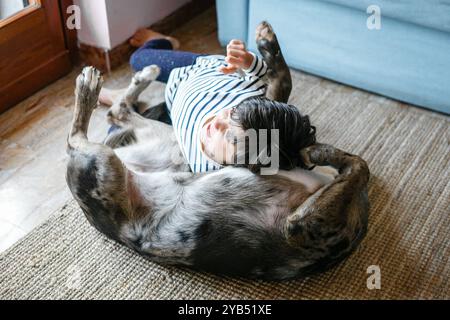 vue en angle élevé de l'enfant jouant avec le chien, couché sur le dos Banque D'Images