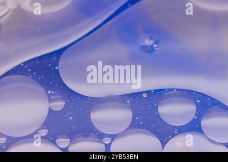 Cette photo macro présente un fond abstrait avec une teinte bleue, orné de gouttelettes d'eau de différentes tailles. Banque D'Images