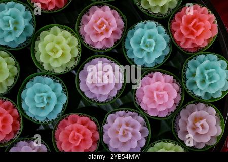 Gâteaux à la farine sucrée thaïlandaise Khanom Phakakrong colorés avec remplissage de haricots mungo, en forme de délicates fleurs de Lantana, servis dans des tasses de feuilles de banane Banque D'Images