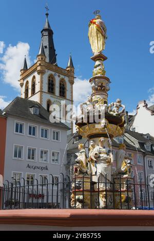Fontaine baroque avec des sculptures détaillées devant une tour historique dans la vieille ville, Petrusbrunnen et l'église St Gandolf, Hauptmarkt, Trèves, Rhinel Banque D'Images