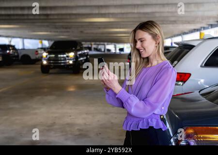 Un magnifique modèle blond se rend à sa voiture dans un garage couvert après une réunion réussie Banque D'Images