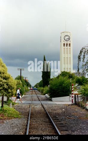 Ligne de chemin de fer passant par la ville de Hastings en Nouvelle-Zélande et la Hastings Clock Tower, un monument public conçu par Sidney George Chaplin, et érigé en 1935. La tour est située dans le quartier central des affaires de Hastings, le long de la ligne de chemin de fer Palmerston North-Gisborne adjacente à l'intersection des rues Heretaunga et Russell. La tour de l'horloge a été conçue comme un symbole de récupération après le tremblement de terre de Hawke's Bay de 1931 Banque D'Images