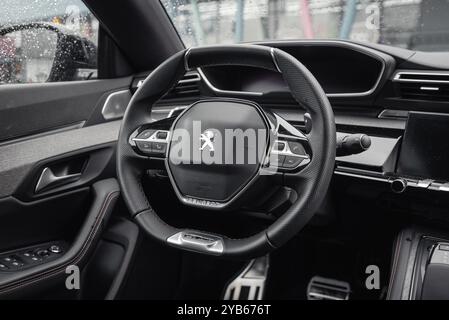 Intérieur gris foncé de la Peugeot 508. Vue rapprochée du volant et du tableau de bord à l'intérieur de l'élégante berline Peugeot. Banque D'Images