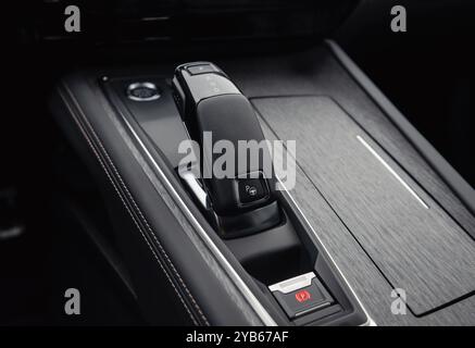 Sélecteur de vitesse automatique dans une voiture de luxe. Intérieur de l'automobile dans les tons sombres, vue rapprochée de la partie inférieure de la console centrale. Banque D'Images