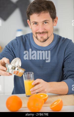 bel homme presse les oranges pour le jus Banque D'Images