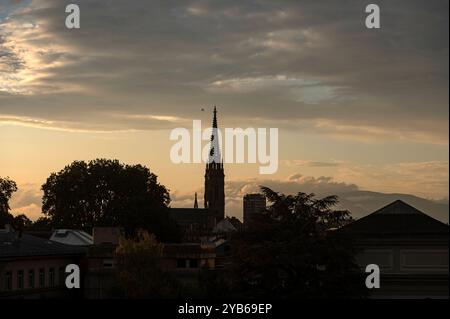 Mulhouse France 23 septembre 2024. Des nuages époustouflants baignent la ville française de Mulhouse alors que le soleil se couche à l'ouest. Temple Saint-Etienne silhouetté par les teintes dorées au-delà. soirée, crépuscule, église, clocher, Banque D'Images