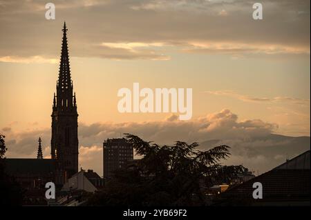 Mulhouse France 23 septembre 2024. Des nuages époustouflants baignent la ville française de Mulhouse alors que le soleil se couche à l'ouest. Temple Saint-Etienne silhouetté par les teintes dorées au-delà. soirée, crépuscule, église, clocher, Banque D'Images