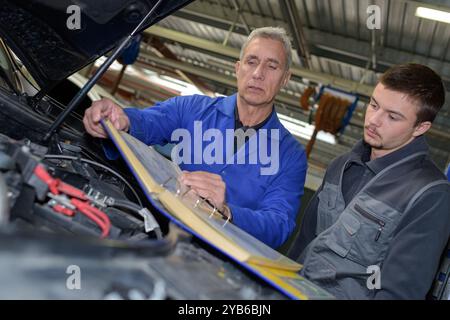 mécaniciens masculins travaillant sur le moteur de voiture Banque D'Images