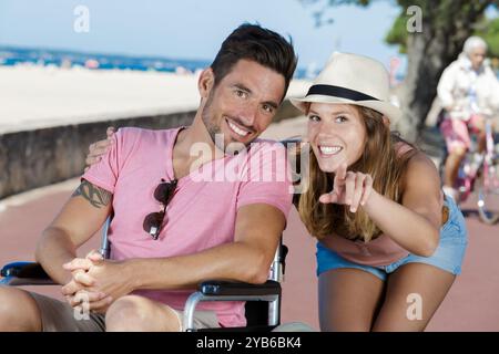 homme paraplégique en fauteuil roulant et sa copine pointant Banque D'Images