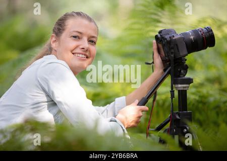 belle fille souriante utilisant la caméra sur trépied dans la campagne Banque D'Images