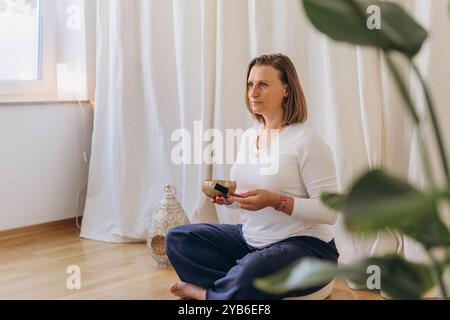 Jeune femme jouant sur un bol tibetian chantant. Relaxation et méditation. Thérapie sonore, médecine alternative. Photo de haute qualité Banque D'Images