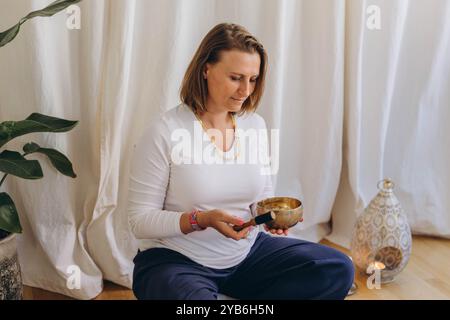 Jeune femme jouant sur un bol tibetian chantant. Relaxation et méditation. Thérapie sonore. Photo de haute qualité Banque D'Images