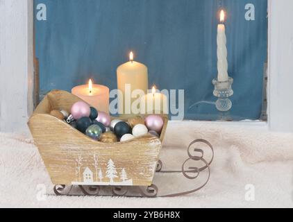 Décoration de Noël vintage avec petit traîneau avec cadre de fenêtre et bougies en arrière-plan. Banque D'Images