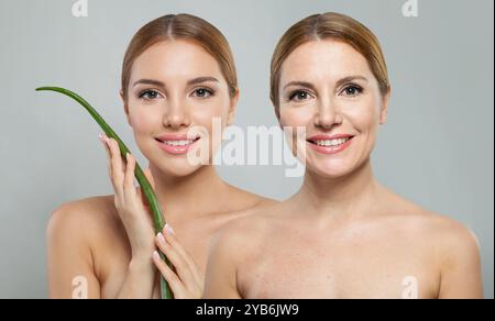 Deux modèles féminins heureux souriants tenant la feuille d'aloe vera sur fond blanc. Soin de la peau, anti-âge et hydratant avec concept cosmétique naturel Banque D'Images