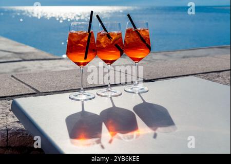 Trois Spritz au soleil devant une mer bleue Banque D'Images