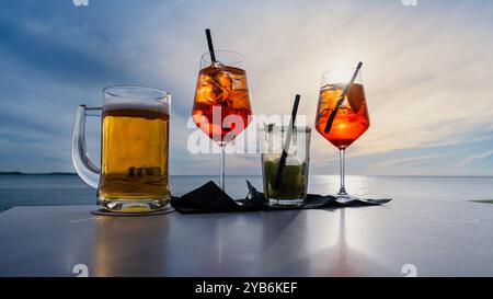 Quatre verres sur une table devant un ciel de coucher de soleil Banque D'Images