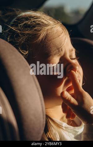 Mignonne petite fille assise dans le siège de sécurité enfant à l'intérieur de la voiture. Photo de haute qualité Banque D'Images