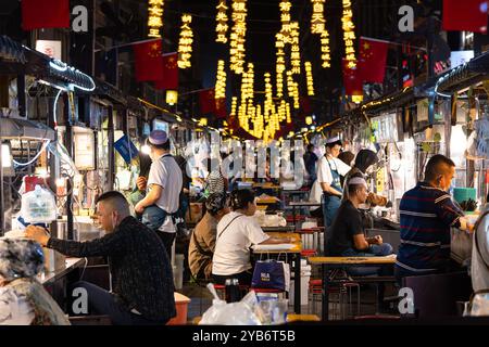 Lanzhou, Chine - 24 septembre 2024 : les gens apprécient la cuisine chinoise dans la rue Dazhong Xiang la nuit célèbre pour son stand de nourriture dans la ville de Lanzhou en Géorgie Banque D'Images