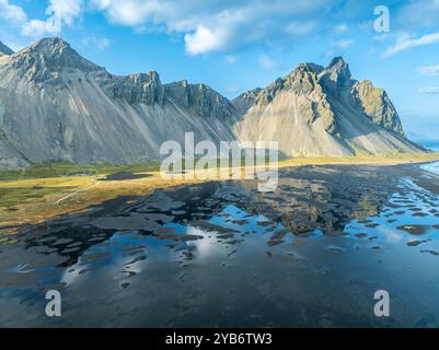 Vue aérienne de Mt. Vestrahorn , plage de lave noire, reflets sur l'eau, Stokksnes, à l'est de Höfn, Fjords de l'est, Islande Banque D'Images