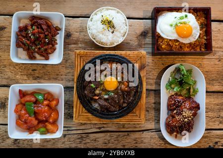 Sélection de plats coréens comprenant bimimbap de bœuf, riz frit au kimchi, poulet aigre-doux et cordes de poulet croustillantes et épicées Banque D'Images