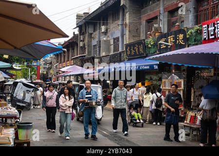 XI'an, Chine - 21 septembre 2024 : les gens marchent dans l'ancienne rue culturelle Shuyuanmen dans la vieille ville de Xi'an près de la porte de la ville Yongningmen avec le mur Banque D'Images