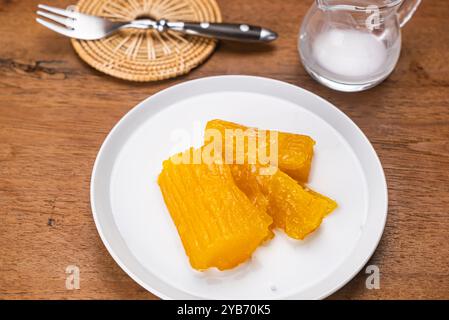 Manioc au sirop. Vue en angle élevé de délicieux manioc maison ou tapioca au sirop dans un plat en céramique blanche sur une table en bois. Banque D'Images