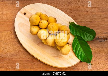 Vue de dessus bouquet de fruits mûrs long Kong ou Longkong (Lansium parasiticum) avec feuille verte sur planche de bois sur table en bois. Banque D'Images