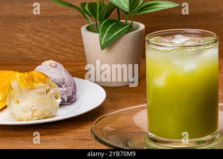 Gros plan sur le jus de goyave vert froid avec glaçon en verre transparent sur soucoupe en verre avec gâteau de lune chinois multicolore et cak en couches Banque D'Images