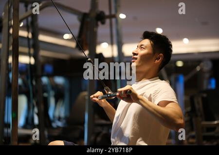 Belle séance d'entraînement de jeune homme asiatique et exercice dans la salle de gym. vue latérale Banque D'Images