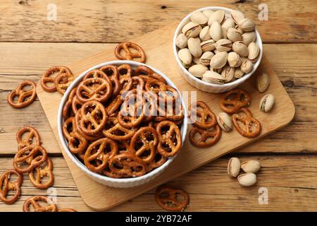 Délicieux bretzel craquelins et pistaches sur table en bois, plat Banque D'Images