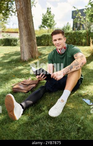 Un jeune homme avec une jambe prothétique se détend dehors, lisant un livre et profitant de la journée ensoleillée. Banque D'Images