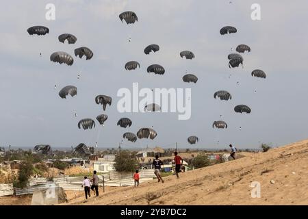 Al Mawasi, Territoires palestiniens. 17 octobre 2024. Les Palestiniens déplacés font la course pour recevoir de l'aide alimentaire, alors que les colis d'aide humanitaire émiratis atterrissent en parachute dans la région d'Al-Mawasi, à l'ouest de la ville de Khan Yunis, dans le sud de la bande de Gaza. Crédit : Abed Rahim Khatib/dpa/Alamy Live News Banque D'Images