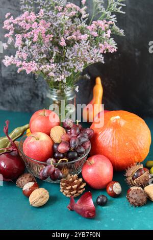 Réconfortez les ingrédients alimentaires sur une table. Nature morte colorée avec citrouille, pommes, noix et fleurs. Concept de récolte d'automne. Banque D'Images