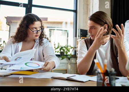 Deux amis participent à une discussion animée tout en examinant des documents à un bureau partagé. Banque D'Images